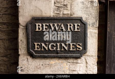 Fate attenzione al cartello in ghisa vittoriana dei motori in una sala macchine a vapore. Steampunk, stile retrò, può essere usato per rappresentare la paura delle macchine e i artificiali Foto Stock