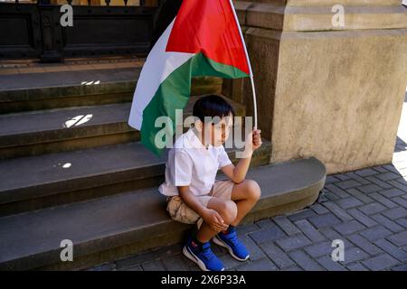 Un ragazzo palestinese detiene una bandiera palestinese durante la prima manifestazione in Polonia organizzata da studenti e studiosi contro l'attacco israeliano alla Striscia di Gaza di fronte al Collegium Novum, l'ufficio del decano dell'Università Jagellonica a Cracovia, in Polonia, il 15 maggio 2024. Foto Stock