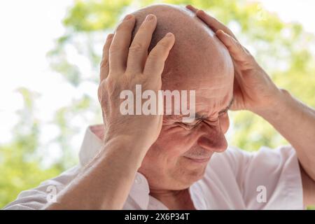 Uomo maturo malato, senior sperimenta un forte mal di testa, tenendo la testa, diminuita memoria e concentrazione, esausto, menopausa, crisi di mezza età Foto Stock