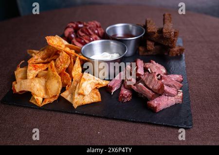 Vista dall'alto di un piatto di cibo con pane, carne, salsiccia e patatine fritte con salsa. Foto Stock