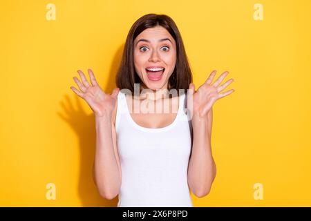 Foto di una signora vestita di bianco che urla le braccia in ascesa a bocca aperta sfondo giallo isolato Foto Stock