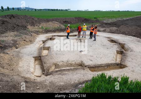 Nauendorf, Germania. 16 maggio 2024. In un campo vicino a Nauendorf vicino ad Halle, i partecipanti ad un evento organizzato dall'Ufficio statale Sassonia-Anhalt per la conservazione dei monumenti e dell'archeologia si trovano nella pianta di un rifugio mortuario di 6000 anni. La persona sepolta qui e' stata trovata in una posizione accovacciata e sdraiata sul suo lato destro. Il corpo è sepolto in una pianta trapezoidale di una precedente capanna mortuaria. Gli archeologi hanno trovato due di queste capanne mortuarie risalenti a 6000 anni fa qui. I tumuli funerari appartengono alla cultura di Baalberg. Crediti: Hendrik Schmidt/dpa/Alamy Live News Foto Stock