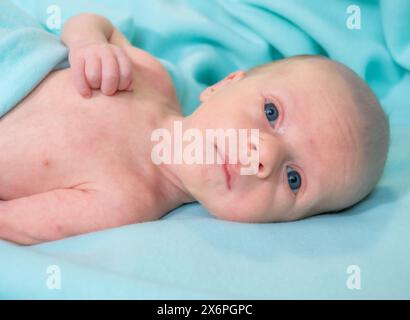 Neonato disteso su morbida coperta in acqua nella stanza dell'ospedale, giorno Foto Stock