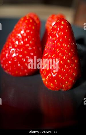 Qualche fragola su un piatto nero Foto Stock