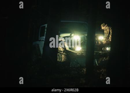 SUV che guida tra gli alberi di notte. Foto Stock