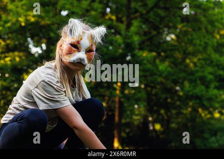 La giovane bambina indossa la maschera pelosa del gatto divertiti a giocare all'aperto nel parco di Forest Street. I bambini hanno un carattere di animali selvatici alla moda Foto Stock