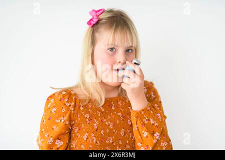 Ritratto di una bella bambina che ha la sindrome di Down usando l'inalatore di asma Foto Stock