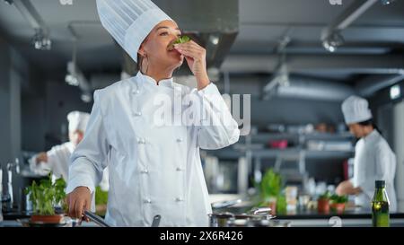 Black Female Chef prende le erbe fresche, le profuma con un sorriso, ingrediente segreto che rende speciale la ricetta della nonna. Cucina tradizionale del ristorante con piatti autentici, cibo salutare e nutriente Foto Stock