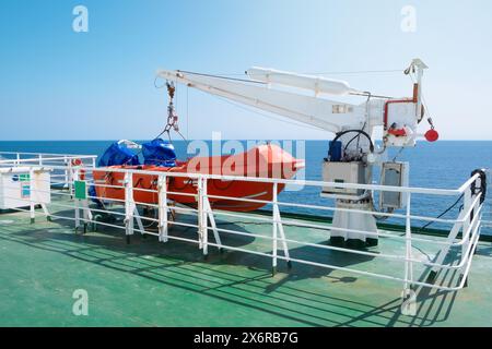 Scialuppa di salvataggio e gru a bordo di un traghetto o di una nave da crociera in mare. Concetto di trasporto e viaggio Foto Stock