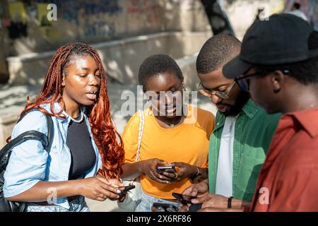 Gruppo serio interessato di studenti neri comunicare condividendo informazioni di studio utilizza smartphone Foto Stock