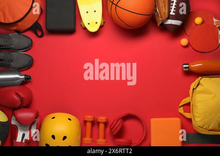 Telaio realizzato con diverse attrezzature sportive su sfondo rosso, piatto. Spazio per il testo Foto Stock