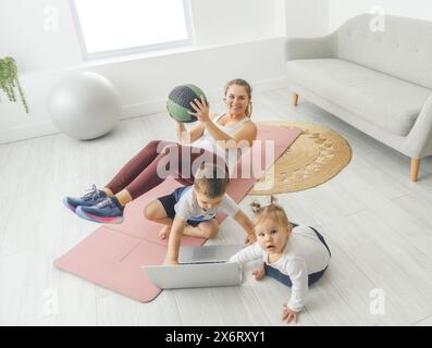 Attività sportive con Baby. La giovane mamma cerca di fare esercizio fisico con suo figlio infantile a casa Foto Stock