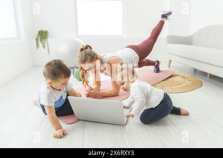 Attività sportive con Baby. La giovane mamma cerca di fare esercizio fisico con suo figlio infantile a casa Foto Stock