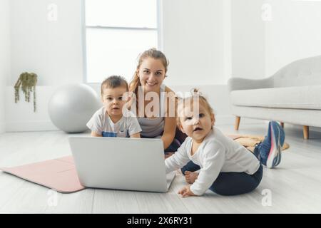 Attività sportive con Baby. La giovane mamma cerca di fare esercizio fisico con suo figlio infantile a casa Foto Stock