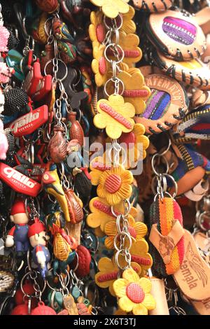 Immagine completa astratta di souvenir, mercato municipale di Antigua, Guatemala. Recuerdos, tieni il sorte, borse, bigiotteria colorata in una banchina del mercato. Niente persone. Foto Stock