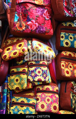 Immagine completa astratta di souvenir, mercato municipale di Antigua, Guatemala. Recuerdos, tieni il sorte, borse, bigiotteria colorata in una banchina del mercato. Niente persone. Foto Stock