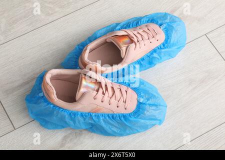 Sneakers da donna in copriscarpe blu su pavimento in legno chiaro, vista dall'alto Foto Stock