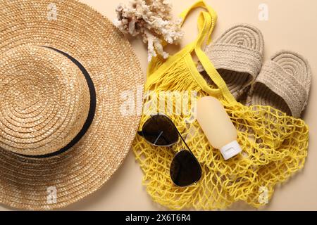 Borsa a cordoncino e diversi accessori da spiaggia sullo sfondo beige, vista dall'alto Foto Stock