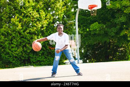 Ritratto del giocatore di basket americano Guy in piedi sul campo da basket con la palla Foto Stock