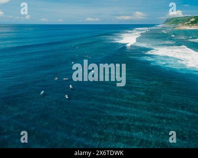 Vista aerea con surfisti sul posto. Onde perfette con surfisti in un oceano cristallino Foto Stock