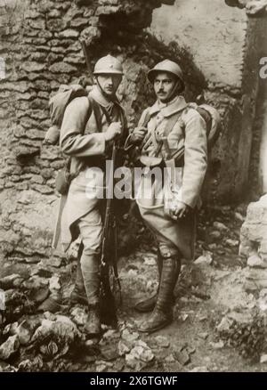 Una fotografia di due fanti francesi che indossano un abbigliamento militare tradizionale e caschi in acciaio in stile medievale, scattata durante la prima guerra mondiale, intorno al 1915. Gli elmetti, noti come elmetti Adrian, sono stati introdotti per proteggere i soldati da schegge e ferite alla testa, riflettendo la natura in evoluzione dell'equipaggiamento militare in risposta alle dure condizioni della guerra di trincea. Foto Stock