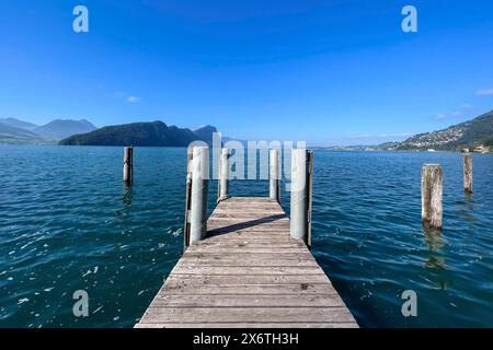 Il molo di legno si sporge in un lago limpido sotto il cielo blu, circondato dalle montagne, Vitznau, Lucerna, Svizzera Foto Stock