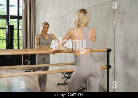 Atleta donna muscolosa in piedi sul corrimano in palestra e guardando allo specchio Foto Stock