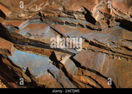 Motivi e strutture blu su strati di formazioni di pietra arenaria a bande nel parco nazionale di Karijini, nella catena di Hamersly, Australia Occidentale Foto Stock