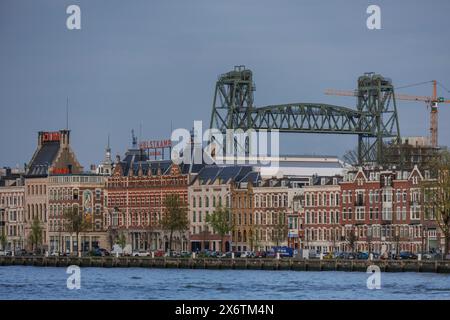 Vista sulla città con vecchi edifici sul fiume e un ponte ferroviario sullo sfondo, skyline di una città moderna sul fiume con un ponte moderno Foto Stock