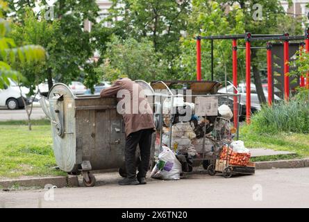 Hungry Man che urla nel cestino. Uomo affamato in cerca di cibo nella spazzatura domestica Foto Stock