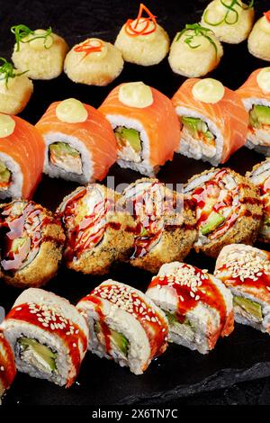Speciali sushi roll disposti su tavola nera Foto Stock