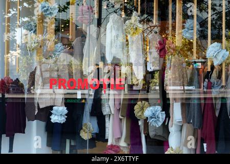 Vetrina del negozio di moda femminile con abiti esposti su grucce e annuncio di promozione delle vendite (“promotie” in rumeno) sui vetri di Bucarest Foto Stock