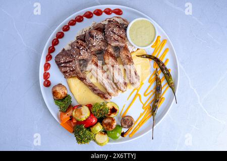 Costolette di agnello grigliate gourmet con verdure e salsa Foto Stock