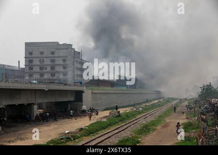 Dacca, Bangladesh. 15 maggio 2024. La gente passa un'area industriale mentre il fumo sale dai mulini rilaminati a Shyampur. Secondo uno studio della Banca mondiale, il Bangladesh deve affrontare un elevato livello di inquinamento atmosferico, che costa circa il 9% del PIL all'anno. La maggior parte dei laminatoi in acciaio all'interno e intorno alla capitale sono stati eseguiti senza il necessario sistema di controllo dell'inquinamento atmosferico che poneva un rischio di inquinamento atmosferico e di pericolo per la salute. (Credit Image: © Suvra Kanti Das/ZUMA Press Wire) SOLO PER USO EDITORIALE! Non per USO commerciale! Foto Stock