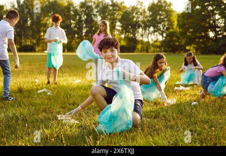 Ritratto di un bambino che raccoglie la spazzatura in un sacco di spazzatura nella foresta o nel parco. Foto Stock