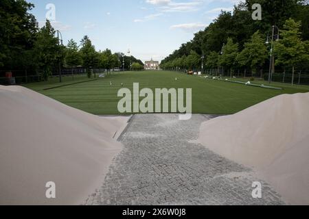 16 maggio 2024, Berlino, Germania: L'attesa per l'UEFA Euro 2024 si sta sviluppando, e da nessuna parte ciò è più evidente che alla porta di Brandeburgo a Berlino il 16 maggio 2024. In una trasformazione senza precedenti, un vasto prato artificiale è stato allestito sull'iconico StraÃŸe des 17. Juni, creando un'oasi verde dove di solito passano migliaia di auto. La zona dei tifosi, destinata a ospitare una delle più grandi feste di calcio di sempre, si estende per circa 24.000 metri quadri e dispone di erba artificiale in polipropilene. Questo ambizioso progetto, che costa circa 1,2 milioni di euro, mira a fornire un vivace e confortevole Foto Stock