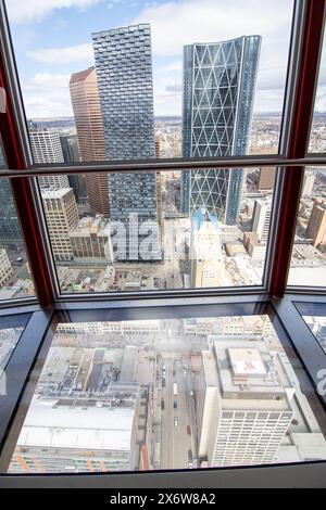 Calgary, Alberta Canada, 3 aprile 2024: Calgary Tower che guarda in basso attraverso la piattaforma di osservazione con pavimento in vetro che si affaccia su edifici e monumenti storici. Foto Stock