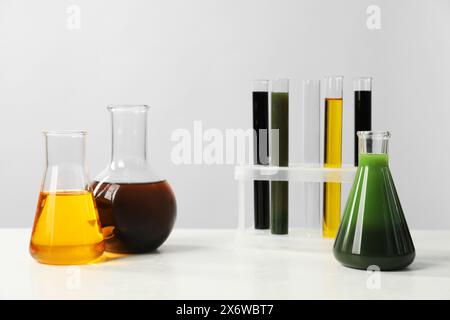 Vetreria da laboratorio con diversi tipi di olio su tavola bianca Foto Stock