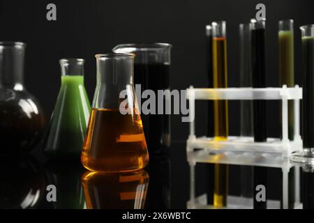 Vetreria da laboratorio con diversi tipi di olio su sfondo nero Foto Stock