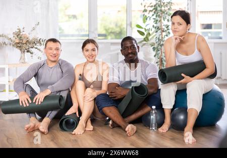 Gruppo di adulti in abbigliamento sportivo con palle da ginnastica in posa nello studio di yoga Foto Stock