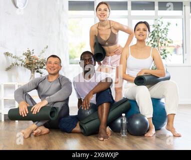 Gruppo di adulti in abbigliamento sportivo con palle da ginnastica in posa nello studio di yoga Foto Stock