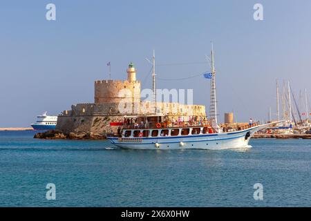 Il tour in barca passa per Fort Saint Nicholas nel porto di Mandraki, Rodi, Grecia, faro e porticciolo Foto Stock