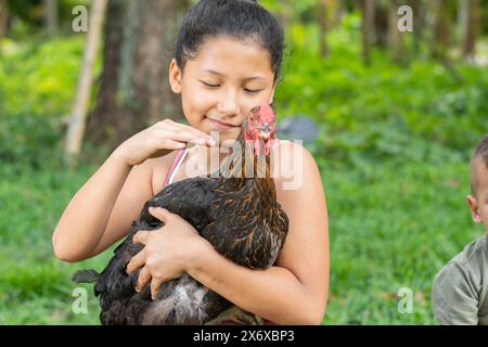 bruna latina che tiene in mano una gallina nera mentre si accarezza e la tratta con amore Foto Stock