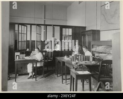Ufficio editoriale, View nell'ufficio editoriale del Deli Courant di Medan. Un giovane uomo e una giovane donna dietro le loro scrivanie, un impiegato giavanese nell'angolo. Parte di un gruppo di 18 foto del 1921 all'interno del gruppo di 49 foto in bianco e nero di diverse dimensioni sulle case editrici e tipografiche del quotidiano Deli Courant a Medan nel periodo 1885-1947., Fotografia, T. Kaneo, (menzionata sull'oggetto), Medan, 1921, supporto fotografico, stampa in argento gelatina, altezza, 150 mm x larghezza, 200 mm Foto Stock