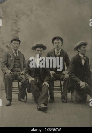 Ritratto di quattro uomini che indossano cappelli, seduti in uno studio con una tela di sfondo dipinto, fotografia, anonima, Stati Uniti d'America, (forse), c. 1880 - c. 1910, metallo, ferrotipizzazione, altezza, 90 mm x larghezza, 60 mm Foto Stock