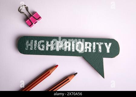 Priorità alta. Bolla verde sulla scrivania bianca dell'ufficio. Foto Stock