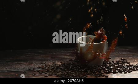 Movimento ultrarapido di ghiaccio che cade nella tazza di caffè e spruzza con sfondo nero separato. Primo piano della goccia di zucchero nell'espresso Foto Stock