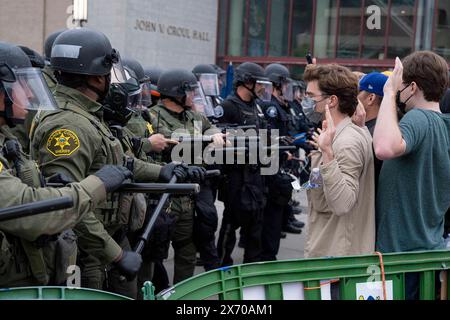 I manifestanti possono essere visti con le mani in alto mentre gli ufficiali Swat procedono verso l'accampamento. Gli agenti di numerose agenzie di polizia della contea di Orange, in California, sono stati chiamati nel campus di Irvine dell'Università della California (UC) per sgombrare un accampamento palestinese in crescita che ha preso il controllo del centro dell'Università. Gli studenti si barricavano in cerchio, fortificando il loro perimetro con pallet di legno e vari altri oggetti per tenere fuori le autorità. Un totale di 50 manifestanti sono stati arrestati con l'accampamento completamente superato dai funzionari di polizia. (Foto di Jon Putm Foto Stock