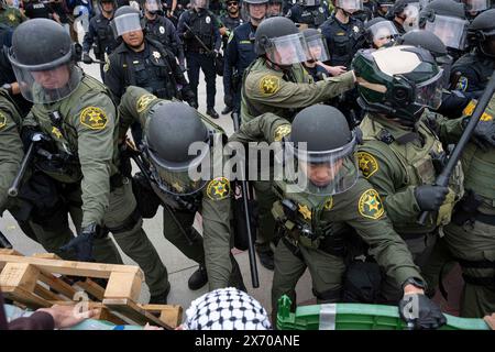 Gli ufficiali SWAT possono essere visti mentre tentano di rompere la barriera all'accampamento dei manifestanti. Gli agenti di numerose agenzie di polizia della contea di Orange, in California, sono stati chiamati nel campus di Irvine dell'Università della California (UC) per sgombrare un accampamento palestinese in crescita che ha preso il controllo del centro dell'Università. Gli studenti si barricavano in cerchio, fortificando il loro perimetro con pallet di legno e vari altri oggetti per tenere fuori le autorità. Un totale di 50 manifestanti sono stati arrestati con l'accampamento completamente superato dai funzionari di polizia. (Foto di Jon Putman/SOPA Images/Sipa Foto Stock