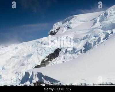 Appeso al ghiacciaio sopra il porto di Mikkelsen, Trinity Island, Antartide Foto Stock